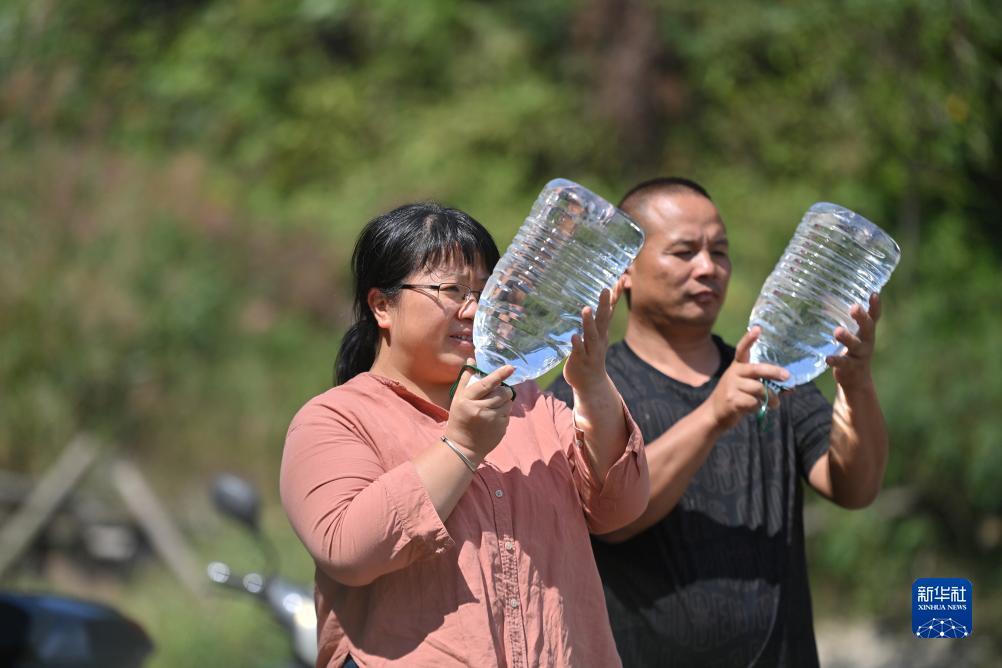 楊寧（左）在查看村民剛剛采集的水樣，為山泉水引水工程做準備（10月8日攝）。新華社記者 黃孝邦 攝